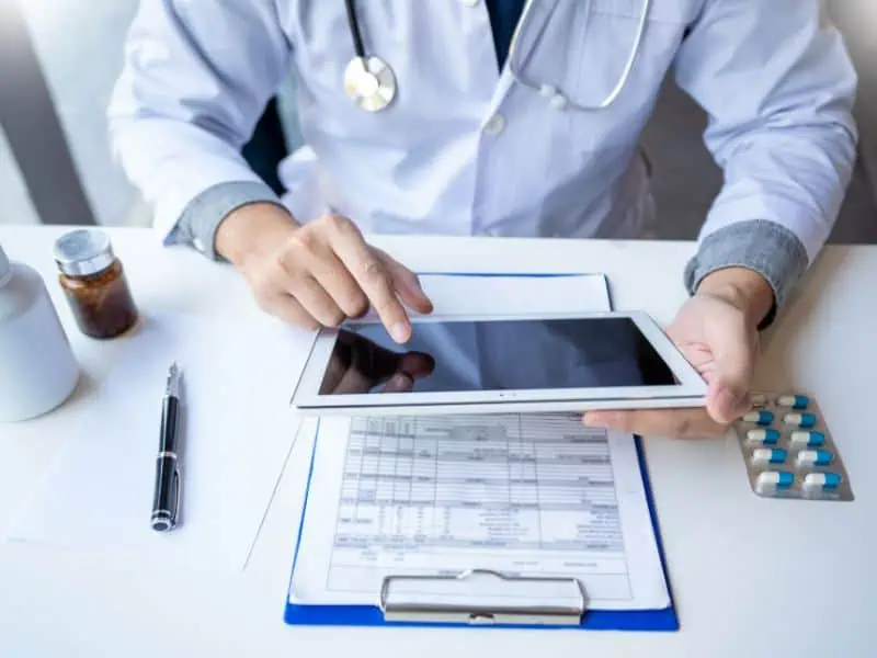 Arzt mit Tablet und Fallakte