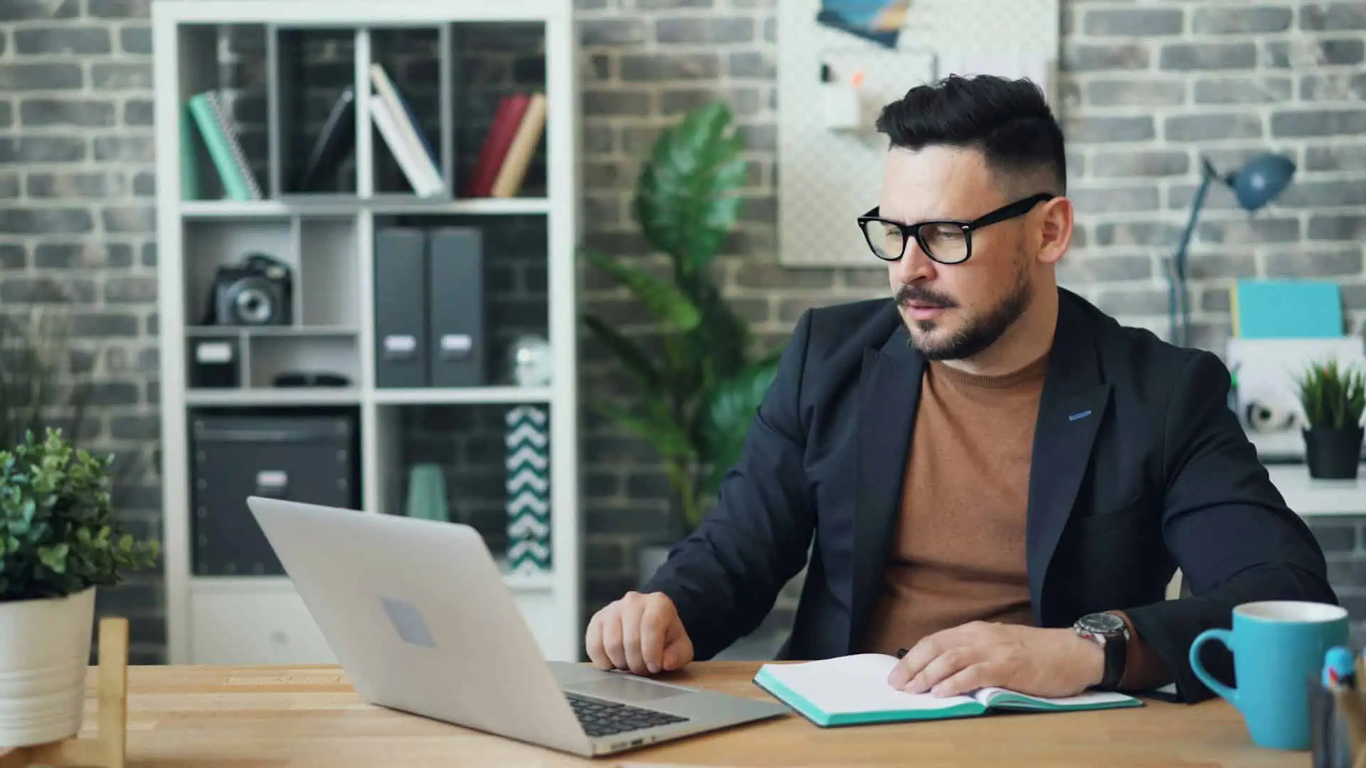 Mann mit Notizbuch vor Laptop